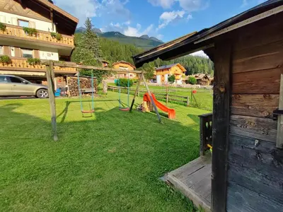 a yard with a playground with a swing at Garofol da Mont-Dolomiti e Relax in Soraga