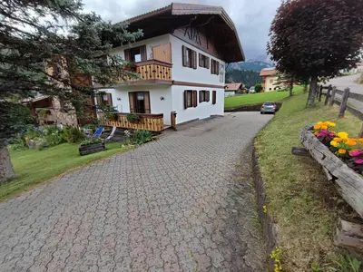 a white house with a porch and a driveway at Garofol da Mont-Dolomiti e Relax in Soraga