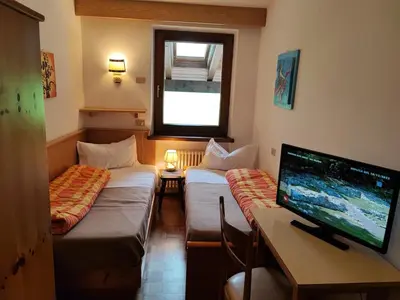 a room with two beds and a desk with a computer monitor at Garofol da Mont-Dolomiti e Relax in Soraga
