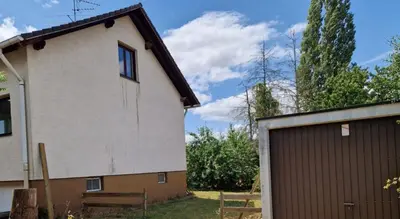 a house with a garage next to a building at Chalet Corallo con camino e ingresso indipendente in Ronco