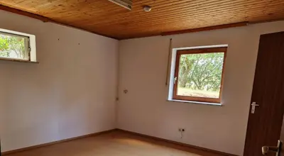 an empty room with a window and a wooden ceiling at Chalet Corallo con camino e ingresso indipendente in Ronco