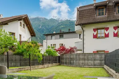 a house with a fence and mountains in the background at Apartment Rosmarin - Alpstay in Naturno