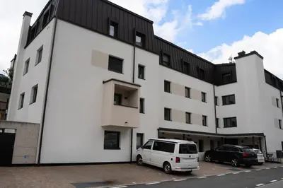 a white building with a white van parked in a parking lot at Apartment Rosmarin - Alpstay in Naturno