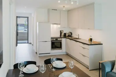a kitchen with white cabinets and a table and chairs at Apartment Rosmarin - Alpstay in Naturno