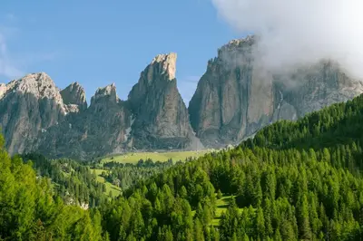 a valley in the mountains with trees and clouds at Casa Massari in Campitello di Fassa