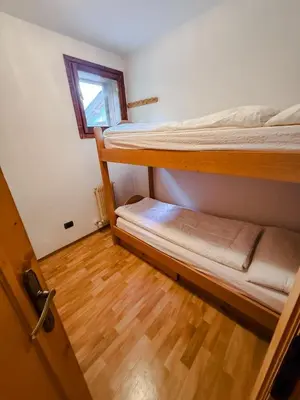 a room with two bunk beds and a wooden floor at Casa Massari in Campitello di Fassa