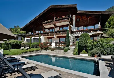 a building with a swimming pool in front of a house at Egger Apartments in Rifiano