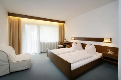 a hotel room with a bed and a chair at Egger Apartments in Rifiano