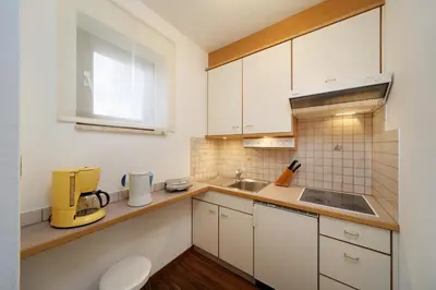 a kitchen with white cabinets and a sink at Egger Apartments in Rifiano