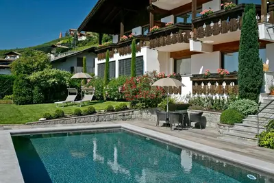a house with a swimming pool in front of a house at Egger Apartments in Rifiano