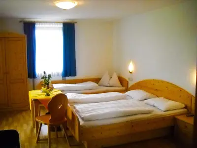 a bedroom with two beds and a table and a window at Gasthof Hohenbichl in Terento