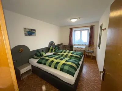 a bedroom with a bed with a green and yellow blanket at Gasthof Hohenbichl in Terento