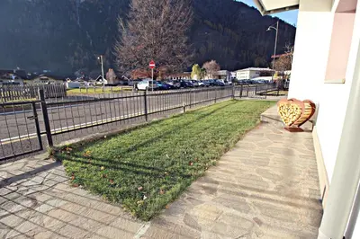 a bench on a sidewalk next to a fence at Guest House Cemin in Predazzo