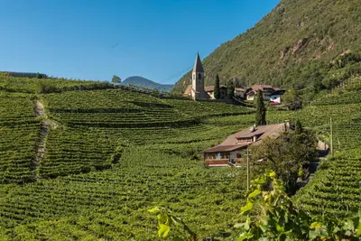 a house on the side of a hill with a church at Untermoserhof in Bolzano