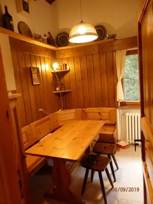 a dining room with a wooden table and a lamp at Mansarda in chalet a Cortina in Cortina dʼAmpezzo