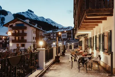 a street with tables and chairs in a town at night at Stella Due in Arabba