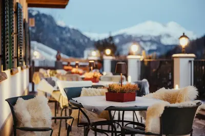 a balcony with tables and chairs with mountains in the background at Stella Due in Arabba
