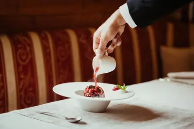 a person pouring sauce on a dessert on a plate at Stella Due in Arabba