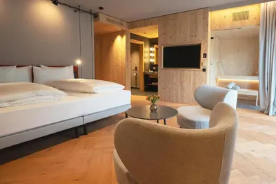 a bedroom with a bed and a living room at La Tambra - Hotel Lodge in Santa Cristina in Val Gardena
