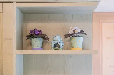 a shelf with three vases and flowers on it at The Cutie Of Dolomites in Falcade