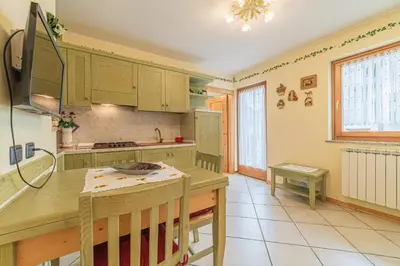 a kitchen with green cabinets and a table at The Cutie Of Dolomites in Falcade