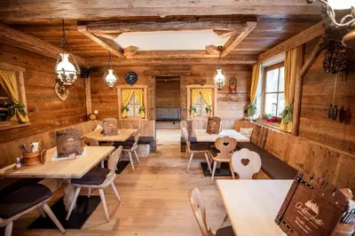 a restaurant with wooden walls and tables and chairs at Grossberghütte in Maranza
