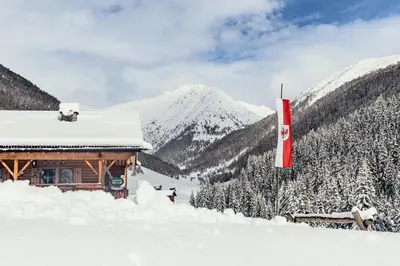 a ski lodge with snow covered mountains in the background at Grossberghütte in Maranza