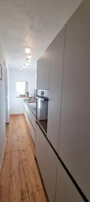 a kitchen with white cabinets and a wooden floor at La Dimora del Sole in Carano