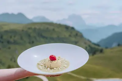 a person holding a white plate with a dessert on it at Rifugio Bec de Roces in Pallua
