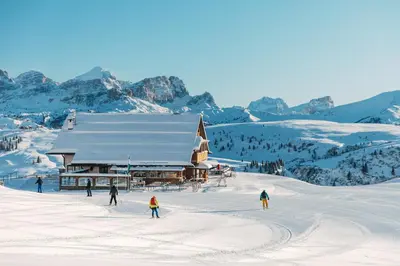 a group of people skiing in the snow in front of a building at Rifugio Bec de Roces in Pallua