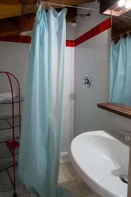 a bathroom with a blue shower curtain next to a sink at Spacious Alpine Loft with Stunning Antelao Views in San Vito di Cadore