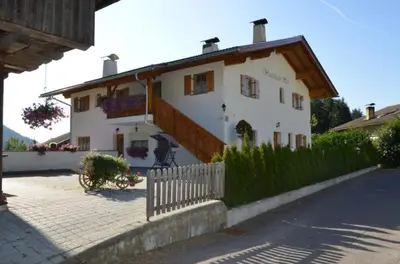 a large white building with a wooden roof at Winterklaubhof in Siusi