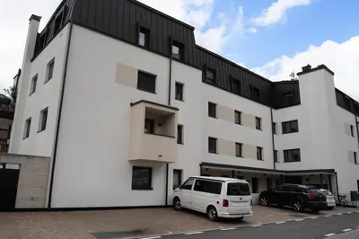 a white building with a white van parked in a parking lot at Apartment Luis 2 - Alpstay in Naturno