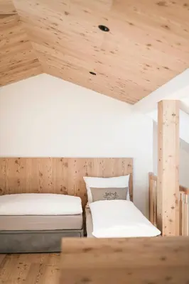two beds in a room with wooden ceilings at Wieserhof Family Farm in Maranza
