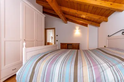 a bedroom with a bed and a wooden ceiling at La Casa di Elvira-Mansarda in Alleghe
