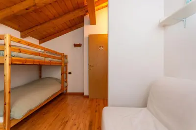 a bedroom with two bunk beds and a couch at La Casa di Elvira-Mansarda in Alleghe