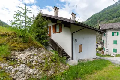 a small white house on a hill next to a building at La Casa di Elvira-Mansarda in Alleghe