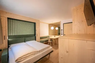a bedroom with a bed and a desk in it at Eden Dolomites in Selva di Val Gardena