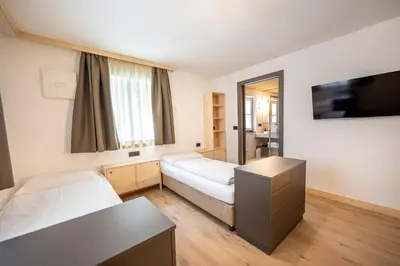 a room with two beds and a flat screen tv at Eden Dolomites in Selva di Val Gardena
