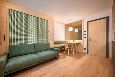 a living room with a green couch and a table at Eden Dolomites in Selva di Val Gardena