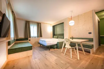 a room with a bed and a desk and a table at Eden Dolomites in Selva di Val Gardena