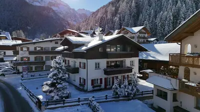 a house with red doors and a bench at Eden Dolomites in Selva di Val Gardena