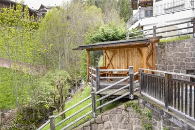 a woodenshed with a wooden fence next to a building at Apartments Ciancel Gino in Ortisei