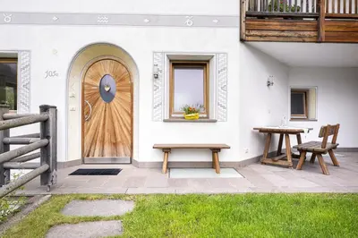 a house with a wooden door and two benches at Apartments Ciancel Gino in Ortisei