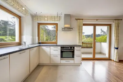 a kitchen with white cabinets and a large window at Apartments Ciancel Gino in Ortisei