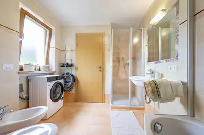 a bathroom with a shower sink and a washing machine at Apartments Ciancel Gino in Ortisei