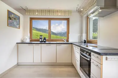 a kitchen with white cabinets and a large window at Apartments Ciancel Gino in Ortisei