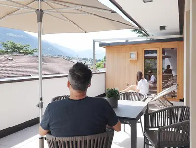 a man sitting at a table under an umbrella at Apartment Luis 3 - Alpstay in Naturno