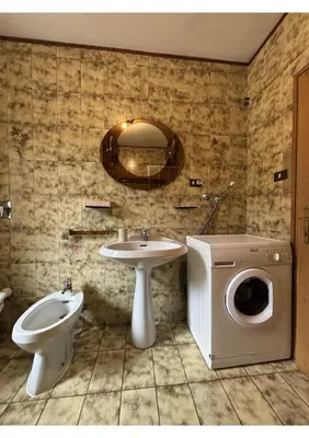 a bathroom with a toilet sink and a washing machine at Appartamento di Nina in Moena
