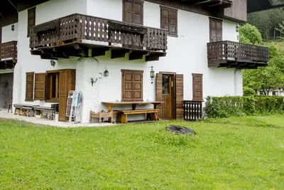 a white house with wooden balconies and a yard at Casa Salvaniera in San Vito di Cadore